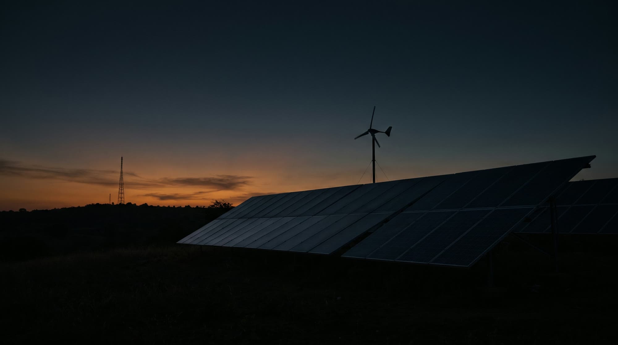 Solar array and wind turbine at dusk — off-grid power infrastructure